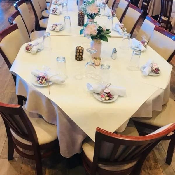 A long dining table set with white tablecloths, floral centerpieces, and place settings for a Davinci's event.