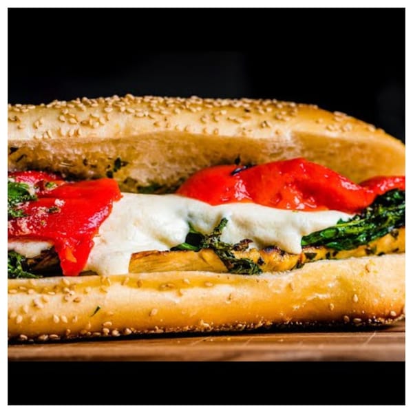 Davinci's Italian sub with melted cheese, red peppers, and greens on a sesame seed roll.